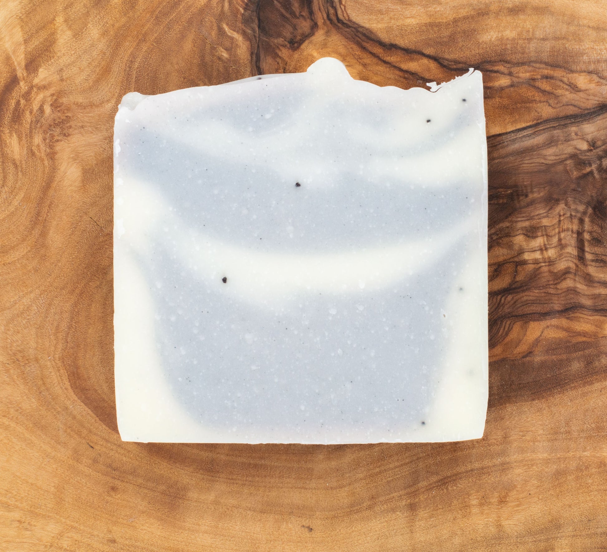 Square piece of white soap on a wooden surface